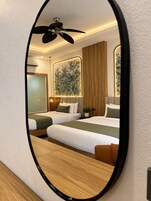 Una habitación de hotel con dos camas, un ventilador de techo, un mural grande en la pared y piso de madera.