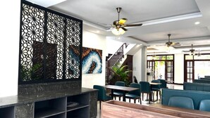 A modern interior with a reception desk, seating area, and decorative wall panels. - Dawn Boutique Luangprabang Hotel (Luang Prabang)