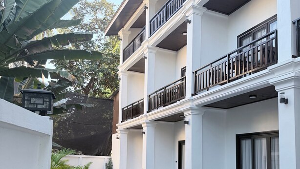 A multi-story hotel with a pool area, featuring balconies with railings, outdoor seating, and a view of the pool. - Dawn Boutique Luangprabang Hotel (Luang Prabang)