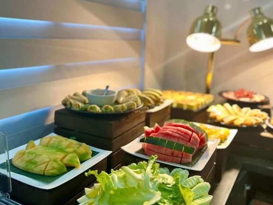 Un bufé con diversos alimentos, entre ellos frutas, verduras y platos preparados.