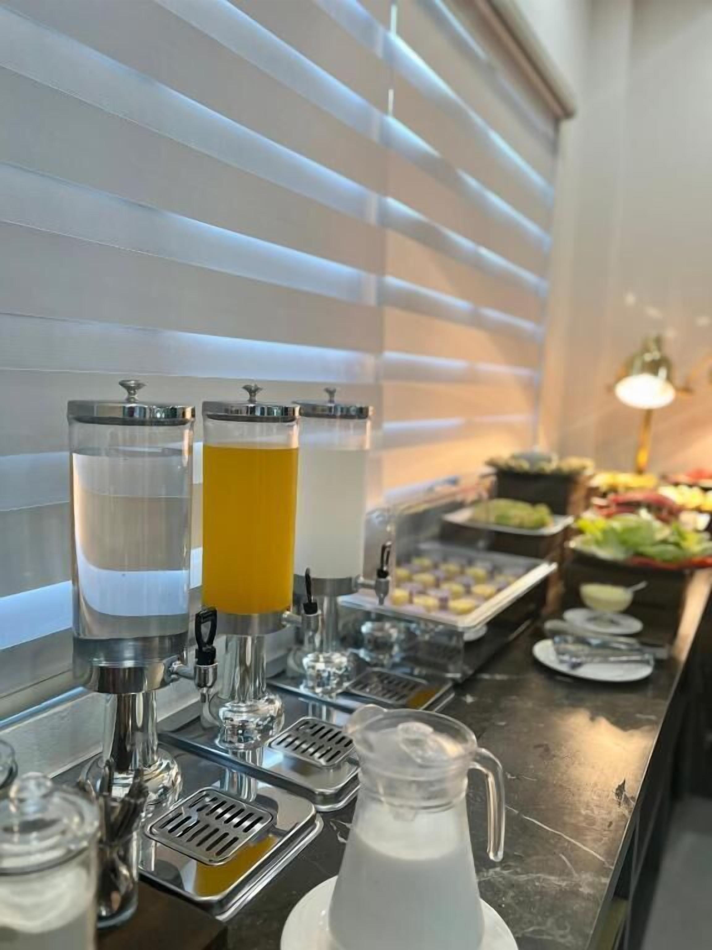 A buffet setup with a beverage station featuring a water dispenser and a pitcher of milk.