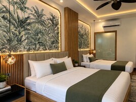 Una camera d'hotel moderna con un letto grande, due comodini, un condizionatore d'aria a parete e una ventola a soffitto.
