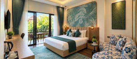 A modern hotel room with a large bed, a seating area with a sofa, a dining table, and a balcony with a view of greenery.