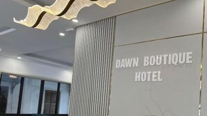 A modern hotel lobby with a reception desk, a decorative light fixture, and a sign reading "DAWN BOUTIQUE HOTEL". - Dawn Boutique Luangprabang Hotel (Luang Prabang)