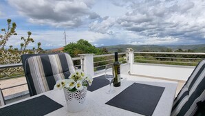 A balcony with two chairs, a table, a bottle of wine, and a vase with flowers. - Villa Kasandra Peace & elegance in Buje, Istria (Kaštel)