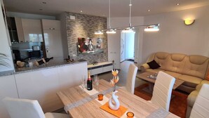 A modern living room with a dining area, a kitchen in the background, and a sofa with cushions. - Villa Kasandra Peace & elegance in Buje, Istria (Kaštel)