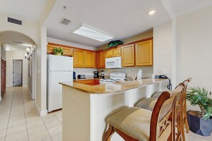 A modern kitchen with wooden cabinets, a central island, and a microwave. - Lake-view 3rd-floor condo with hot tub, pools, balcony, shuttle service, & gyms (Orlando)