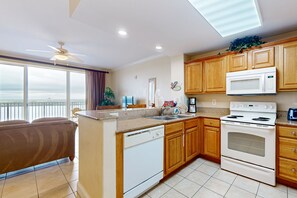 A modern kitchen with wooden cabinets, a built-in microwave, and a dishwasher. - Lovely lakefront condo with lake view, kitchen, pool & hot tub near attractions (Orlando)