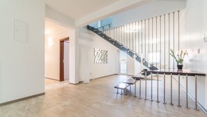 Un ambiente spazioso con una scala moderna, un tavolino e una pianta in vaso.