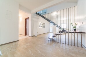 A spacious interior with a modern staircase, a small table, and a potted plant. - Villa Solmaris | Costa da Caparica | Private Pool - Jacuzzi | Near Beach (Lisbon)