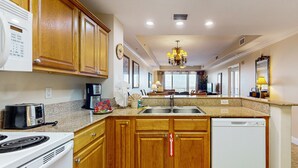Una cocina con armarios de madera, microondas, tostadora, estufa, fregadero y lavavajillas.
