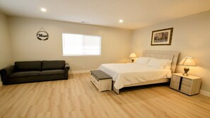 A bedroom with a bed, bedside tables, a nightstand, a bench, a window, and a wall decoration. - New Mountain Estate with Dual Living Spaces | 32 Guests | Perfect for Reunions (Garden City)