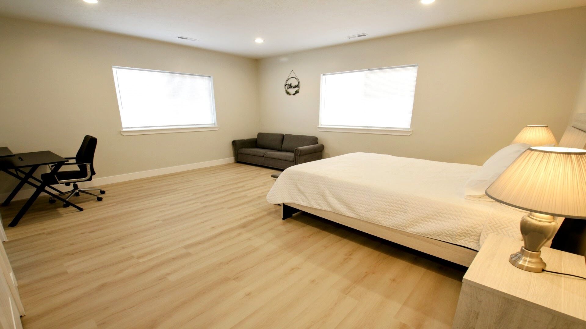 Une chambre à coucher avec un lit, un bureau, une chaise et deux fenêtres.