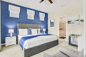 A bedroom with a large bed, bedside tables, a nightstand, a ceiling fan, and a bathroom with a shower and a bathtub. - Spacious resort home with private pool, game room, & abundant  amenities (Davenport)