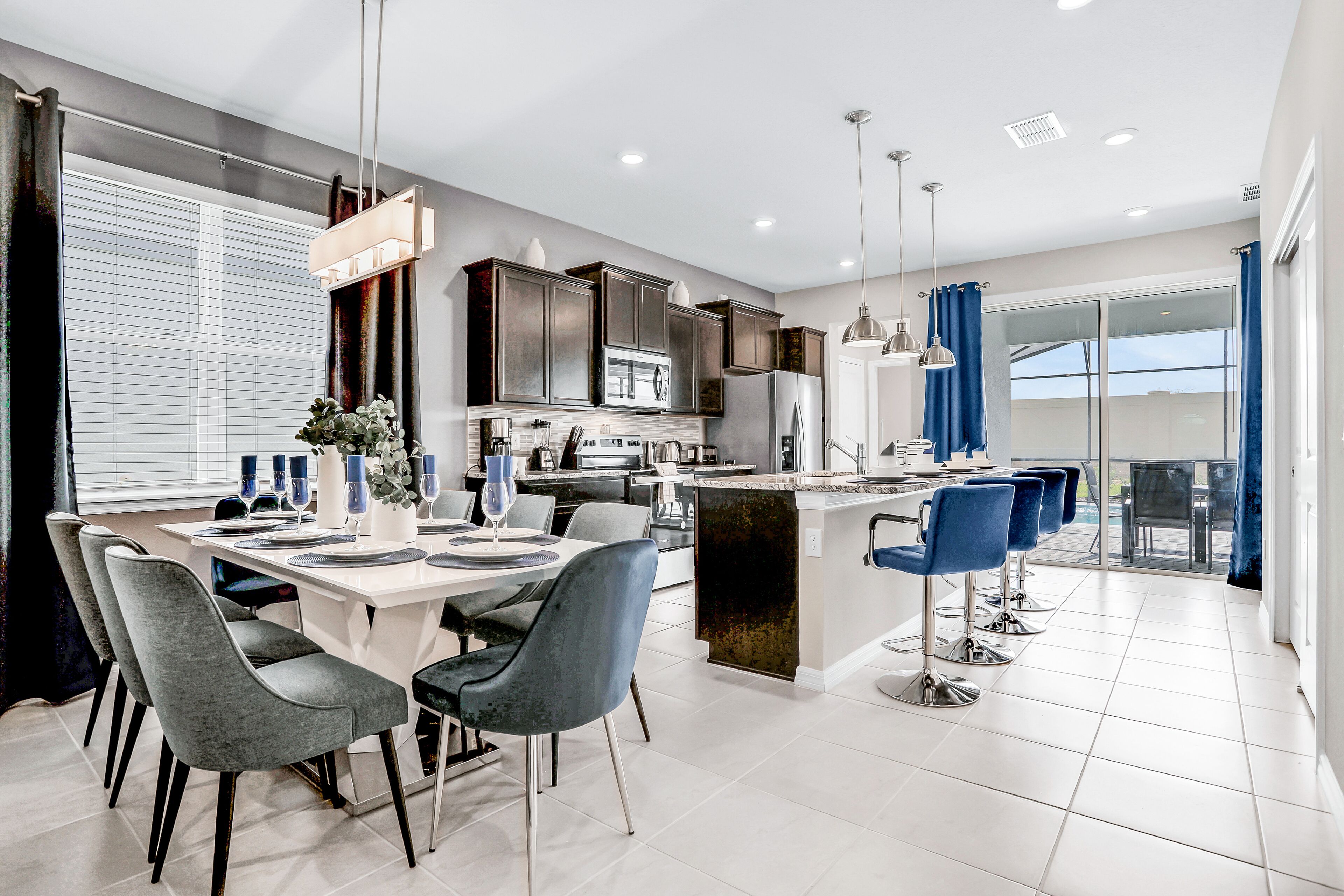 A modern kitchen with dark cabinets, a central island, and blue bar stools.