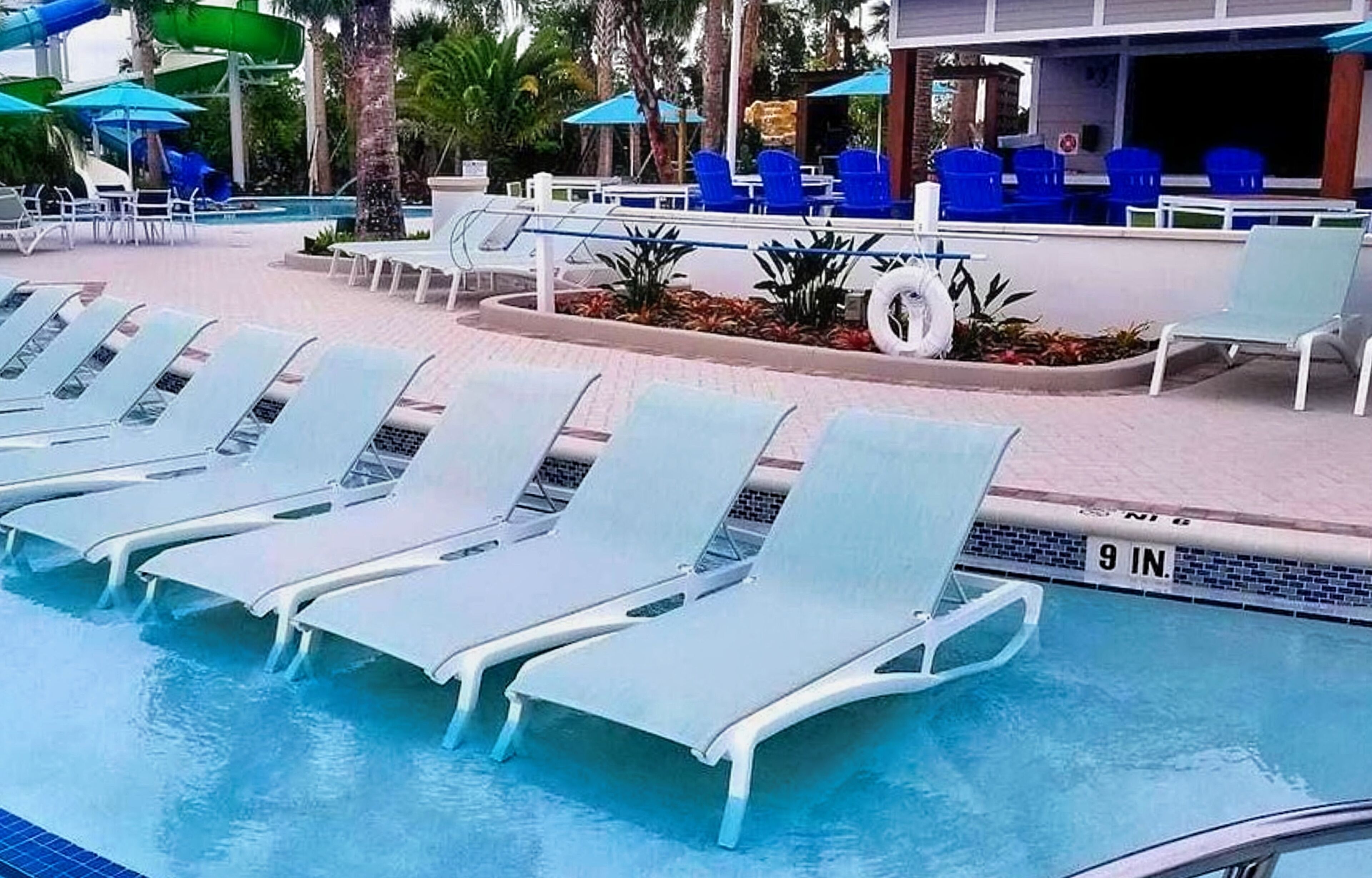 Un área de piscina con sillones reclinables y sombrillas.