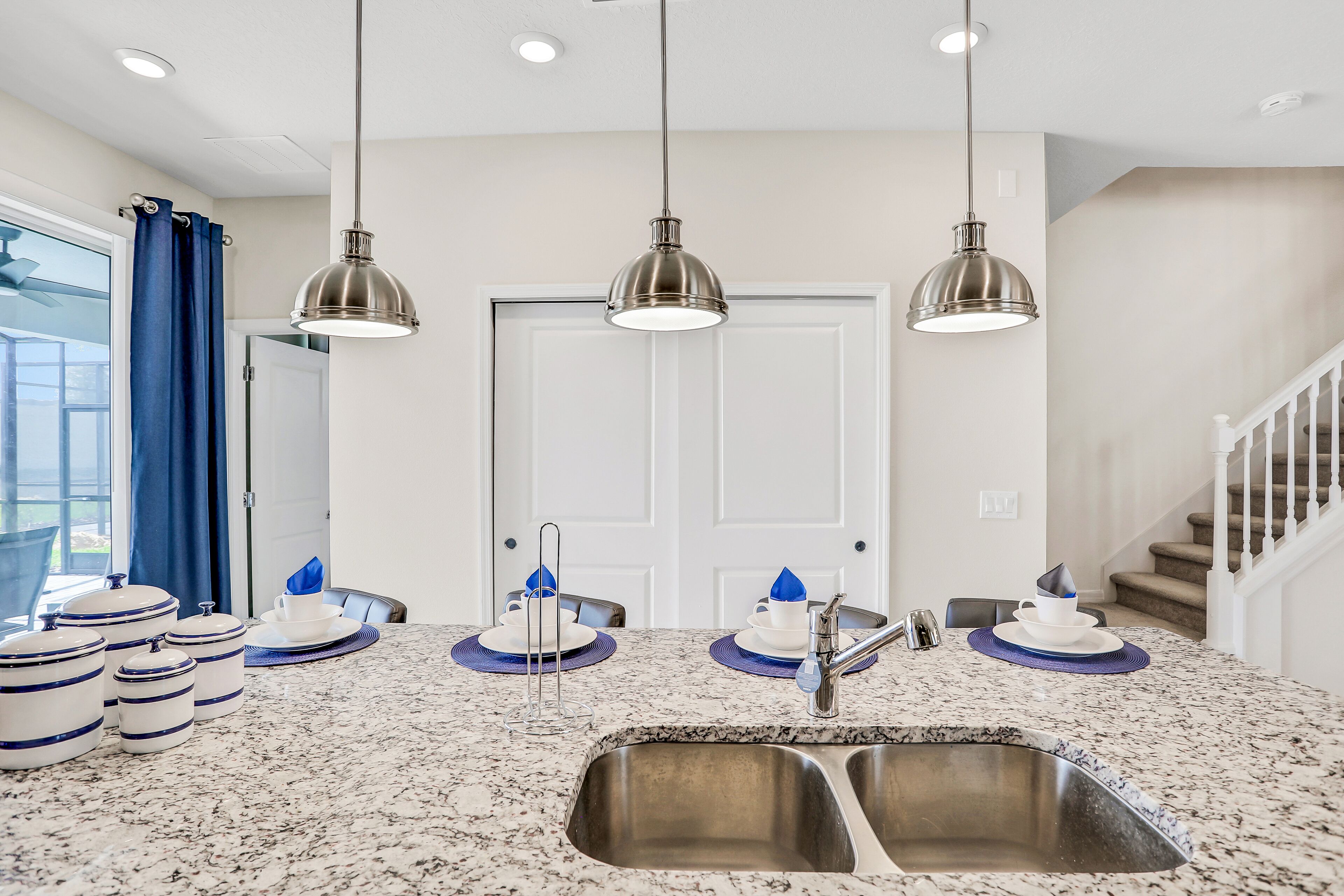A kitchen with a double sink, stainless steel appliances, and pendant lighting.