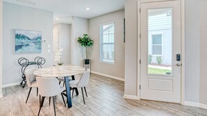 A dining area with a round table and chairs, a potted plant, and a painting on the wall. - Spacious townhome with heated pool, WiFi, & central A/C - near theme parks (Davenport)