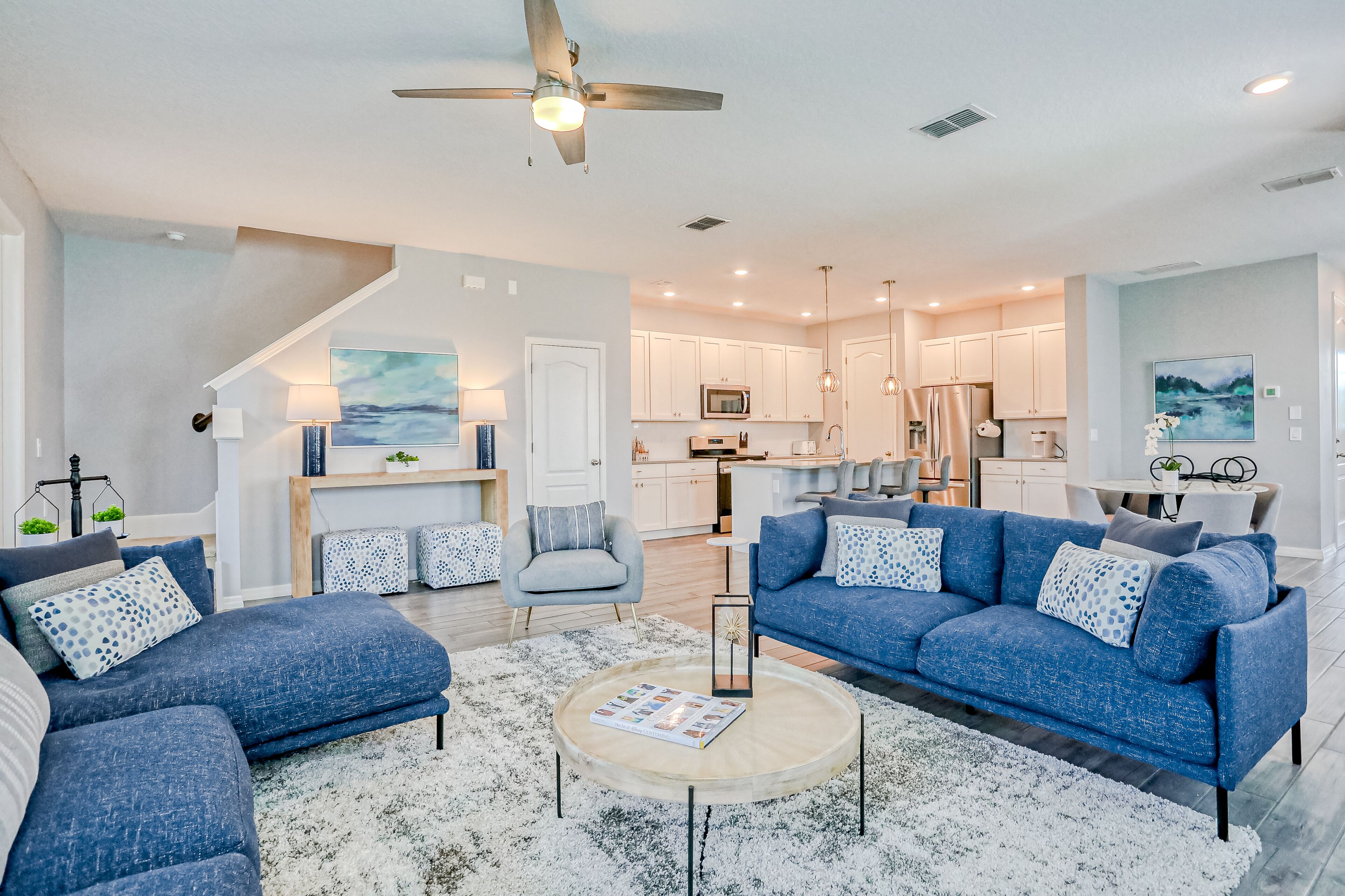 A modern living room with a blue sofa set, a coffee table, and a ceiling fan.