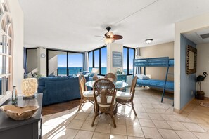 Ein geräumiger Wohnbereich mit Balkon, einem Esstisch mit Stühlen, einer Couch und einem Stockbett.