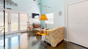 A spacious living room with a high ceiling, a sofa, a table with a lamp, a TV, and a staircase. - Riverfront home with internet, washer and dryer, and perfect for kayaking (Sebring)