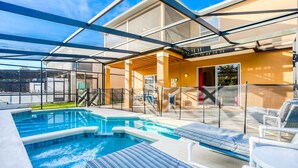 A pool area with a glass-enclosed patio, lounge chairs, and a hot tub. - Gorgeous home near Disney with private pool, pool spa, on-site gym, tennis, AC (Davenport)