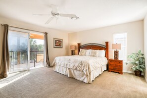 A bedroom with a large bed, a ceiling fan, a nightstand with a lamp, a potted plant, and a sliding glass door leading to a balcony. - 5BR/3BA Davenport home with private pool (Davenport)