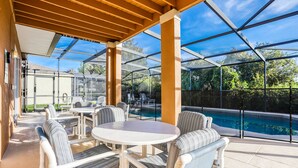 An outdoor patio with a pool, covered seating, and a view of the pool. - Gorgeous home near Disney with private pool, pool spa, on-site gym, tennis, AC (Davenport)