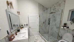 A modern bathroom with a marble floor, a glass-enclosed shower, a toilet, and a sink with a mirror. - Charming 1-bedroom house in excellent Prescott location with AC (Prescott)