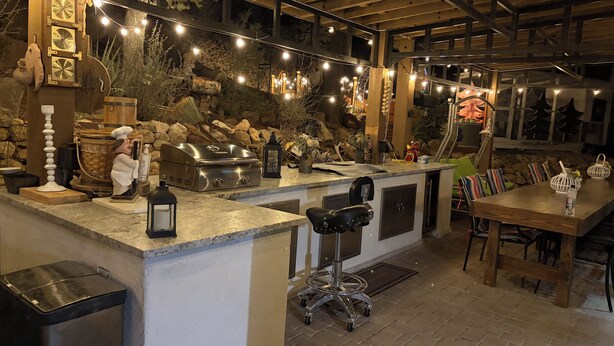 A bar area with a stone wall backdrop, string lights, and a grill station. - Charming 1-bedroom house in excellent Prescott location with AC (Prescott)