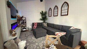 A modern living room with a sectional sofa, a ceiling fan, decorative plants, and a patterned rug. - Charming 1-bedroom house in excellent Prescott location with AC (Prescott)