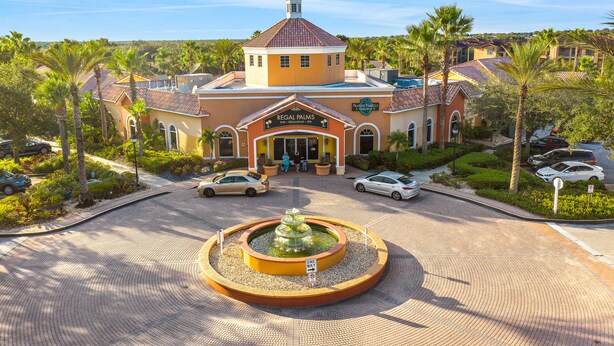 A hotel with a central fountain, palm trees, and a clear blue sky. - Sunny Oasis | Townhouse in Davenport with resort amenities, near Disney (Davenport)