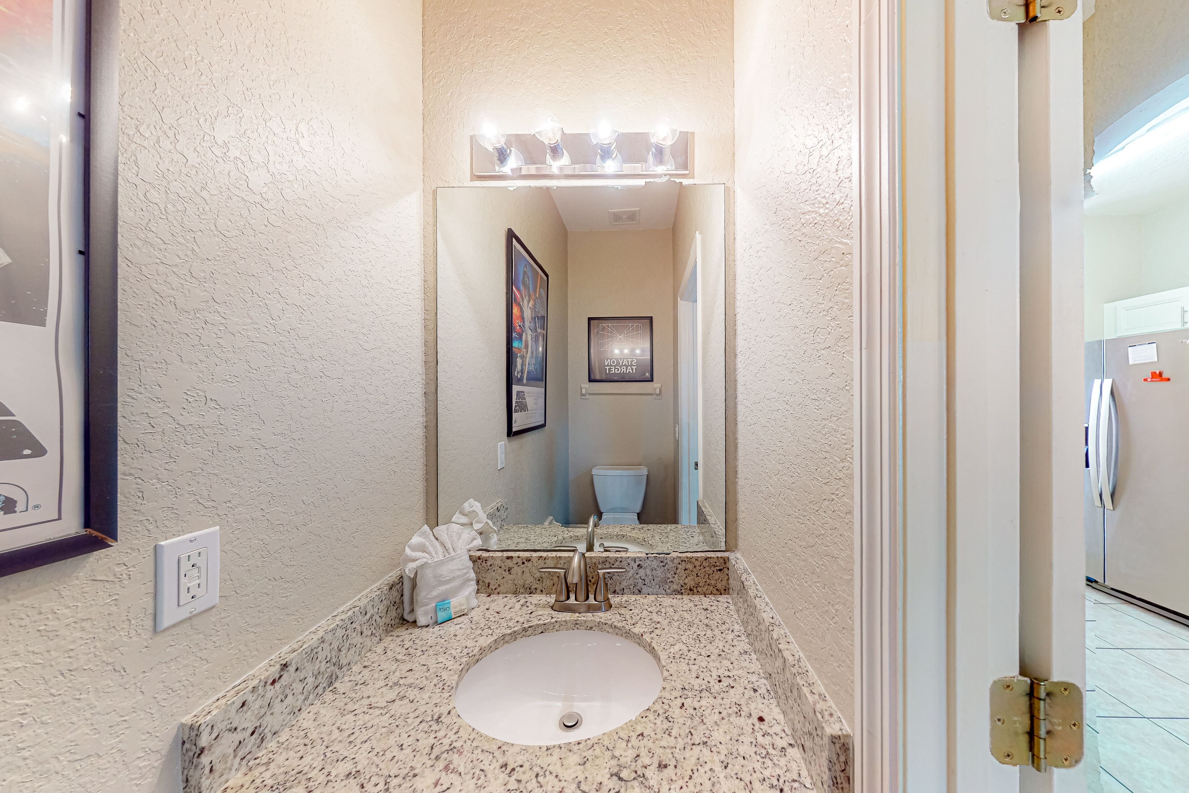 A bathroom with a white sink, a mirror, and a lighted vanity.