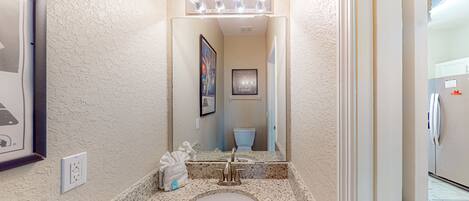 A bathroom with a white sink, a mirror, and a lighted vanity.