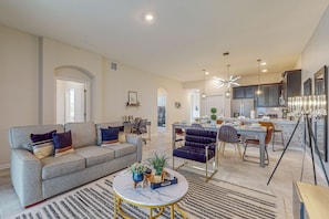 A spacious living area with a sofa, coffee table, and dining table. There is a kitchen in the background with modern appliances and a large island. - Spacious townhouse with private patio and resort amenites (Davenport)