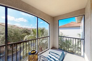 A balcony with a view of a residential area, a striped sofa, and a small table with a lamp. - Calm condo with pool, hot tub, balcony, cabana, & kitchen - snowbird-friendly (Davenport)