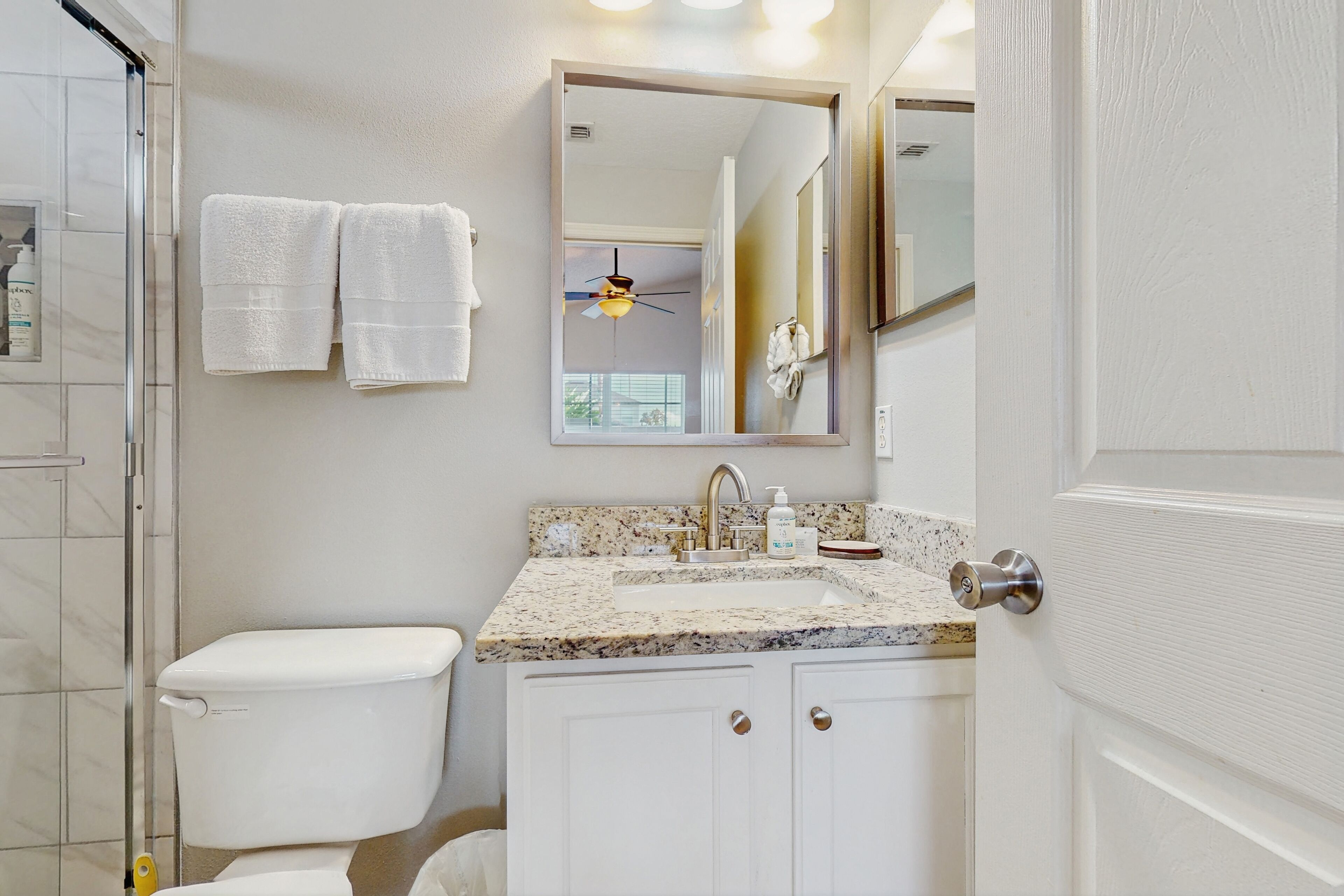 A bathroom with a toilet, sink, and mirror.