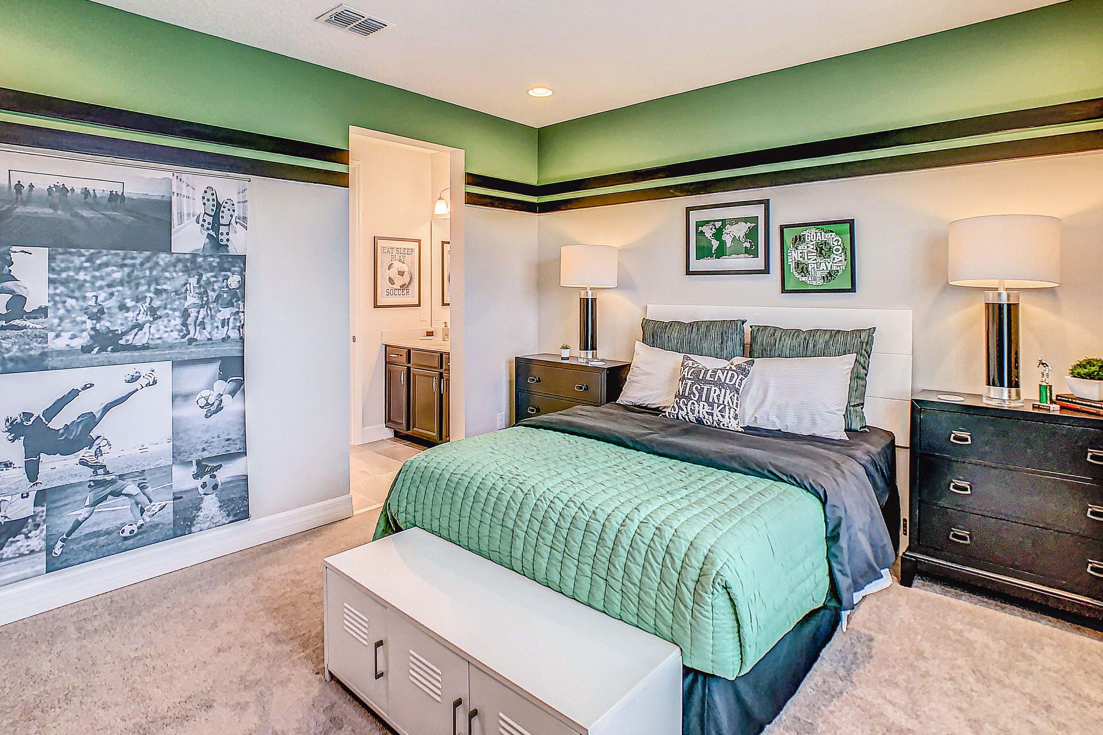 A bedroom with a bed, bedside tables, a dresser, a bench, and wall art.