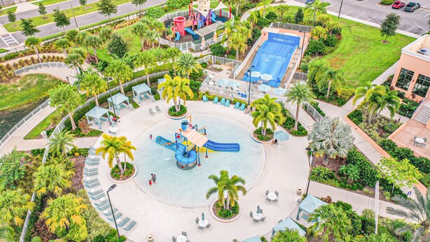 An aerial view of a water park with a central play area, surrounding palm trees, and a pool. - Resort home with private pool, patio, foosball & 2 living areas - near Disney (Kissimmee)