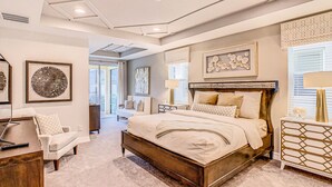 A spacious bedroom with a large bed, a desk, and a chair. - Resort home with private pool, patio, foosball & 2 living areas - near Disney (Kissimmee)