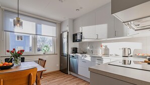 A modern kitchen with white cabinets, a stainless steel refrigerator, a microwave, and a sink. There is a dining table with chairs and a vase of red tulips. - 1 bedroom nice apartment in Huskvarna (Huskvarna)