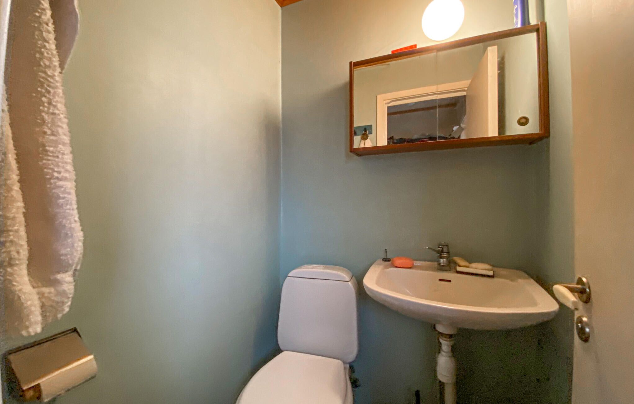 A bathroom with a toilet, sink, and mirror.