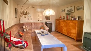 Ein gemütliches Wohnzimmer mit einem braunen Sofa, einem Esstisch mit weißem Tischleinen und einer Holzkabine.