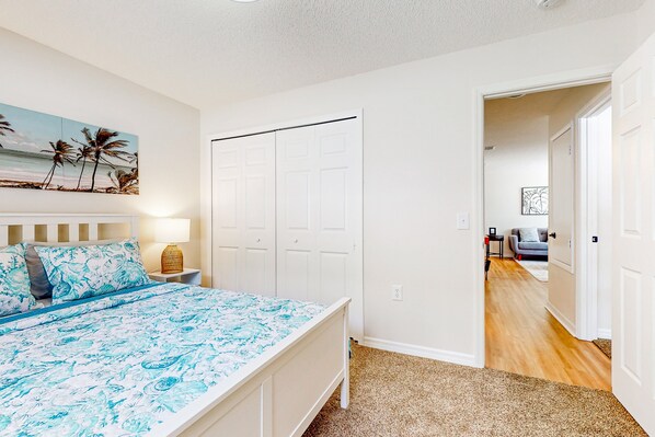 A bedroom with a bed, a nightstand, a lamp, a painting, and a closet. - Single-story house with private pool, alfresco dining, & lanai - dog-friendly (Kissimmee)