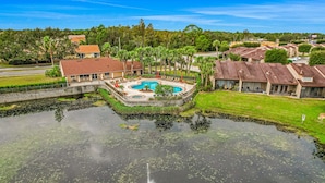 A resort with a swimming pool surrounded by palm trees and a stone wall. - Breezy townhouse with a pool, hot tub, patio, central AC, and washer/dryer (Kissimmee)