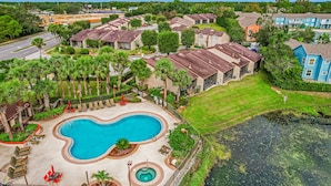 A residential area with a swimming pool, houses, and a small body of water. - Breezy townhouse with a pool, hot tub, patio, central AC, and washer/dryer (Kissimmee)