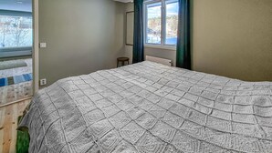 Een slaapkamer met een groot bed, een raam met gordijnen en uitzicht op buiten.