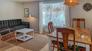 Een gezellige woonkamer met een bank, een bijzettafeltje en een eettafel met stoelen.