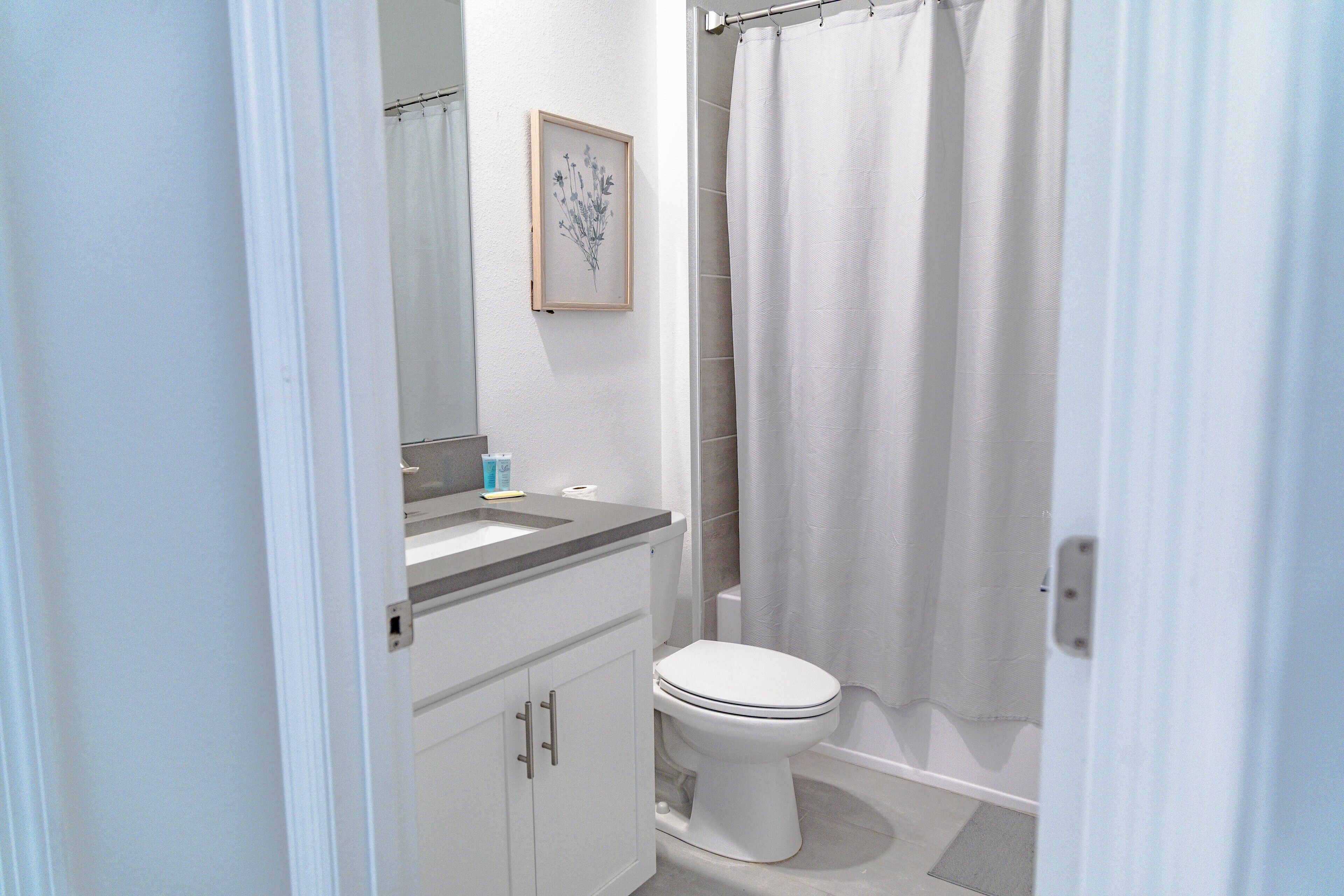 Un baño con inodoro, lavamanos y cortina de ducha.