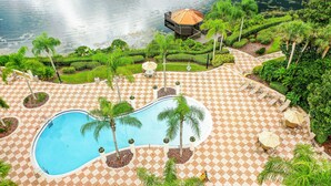 A swimming pool with palm trees, a gazebo, and a checkered patio area. - Two-story, dog-friendly gem near theme parks with pool, central AC & on-site gym (Kissimmee)